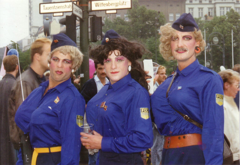 Drei Menschen in FDJ-Bluse und auffällig geschminkt am Wittenbergplatz 1988, Passanten im Hintergrund