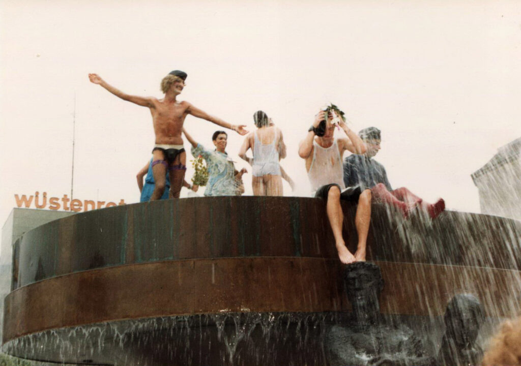 Sieben Menschen tanzen halbnackt und ausgelassen im Brunnen am Wittenbergplatz