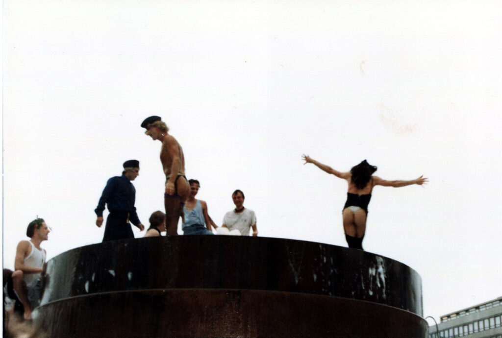 Sieben Menschen tanzen halbnackt und ausgelassen im Brunnen am Wittenbergplatz