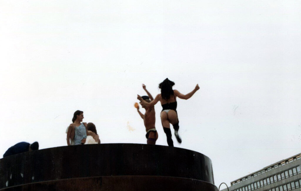 Sieben Menschen tanzen halbnackt und ausgelassen im Brunnen am Wittenbergplatz