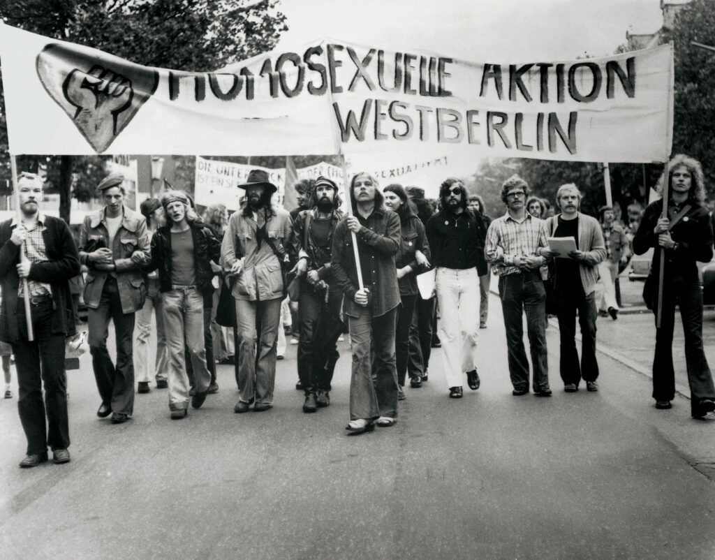 HAW-Pfingstdemonstration am 9. Juni 1973, eine Gruppe von Menschen demonstriert in den Straßen Berlins und trägt ein Banner mit der Aufschrift "Homosexuelle Aktion Westberlin"