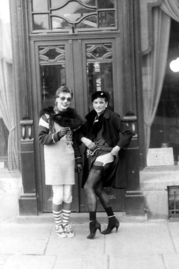 Zwei Tunten im Fummel und Strapsen vor einer Haustür, 1983